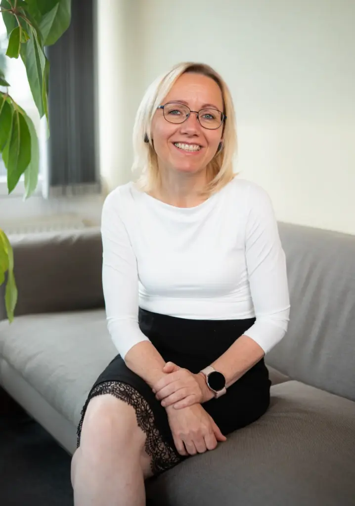 Insa Heller sitzt entspannt und lächelt. Sie ist Buchhalterin für digitale Lohnabrechnung und Nettolohnoptimierung.