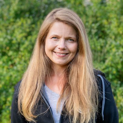 Nicole Kandulski, Inhaberin von Next Level Hundetraining, im Grünen mit langem blondem Haar